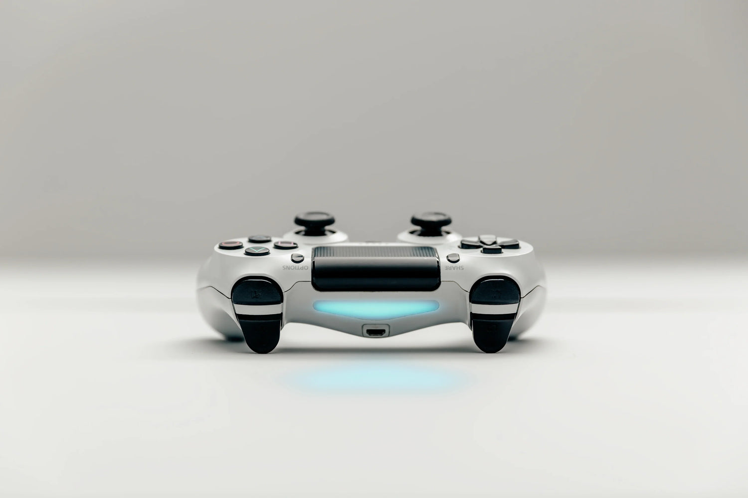 White wireless video game controller with blue light on a plain background, front view