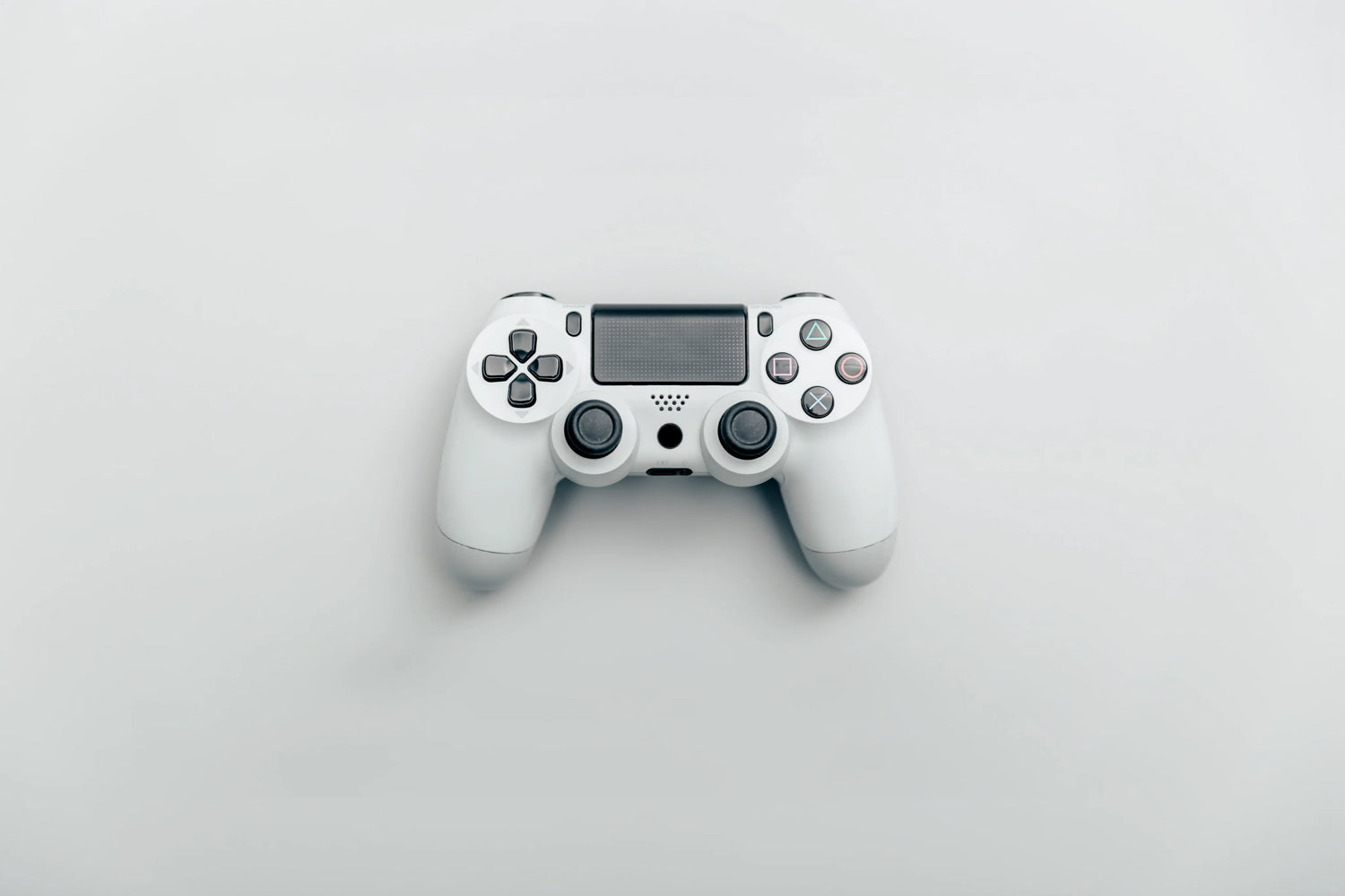 White wireless video game controller on a plain light background, top view